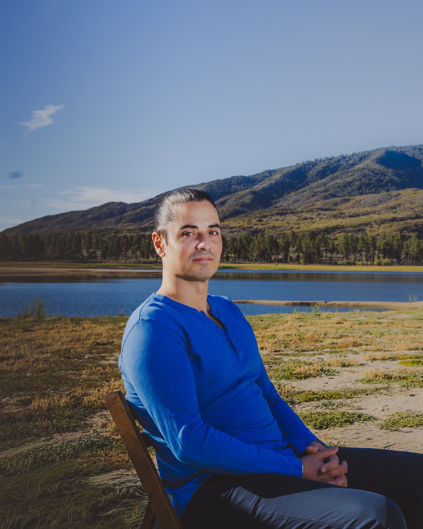 Michael Brabant seated by a lake with mountains behind him